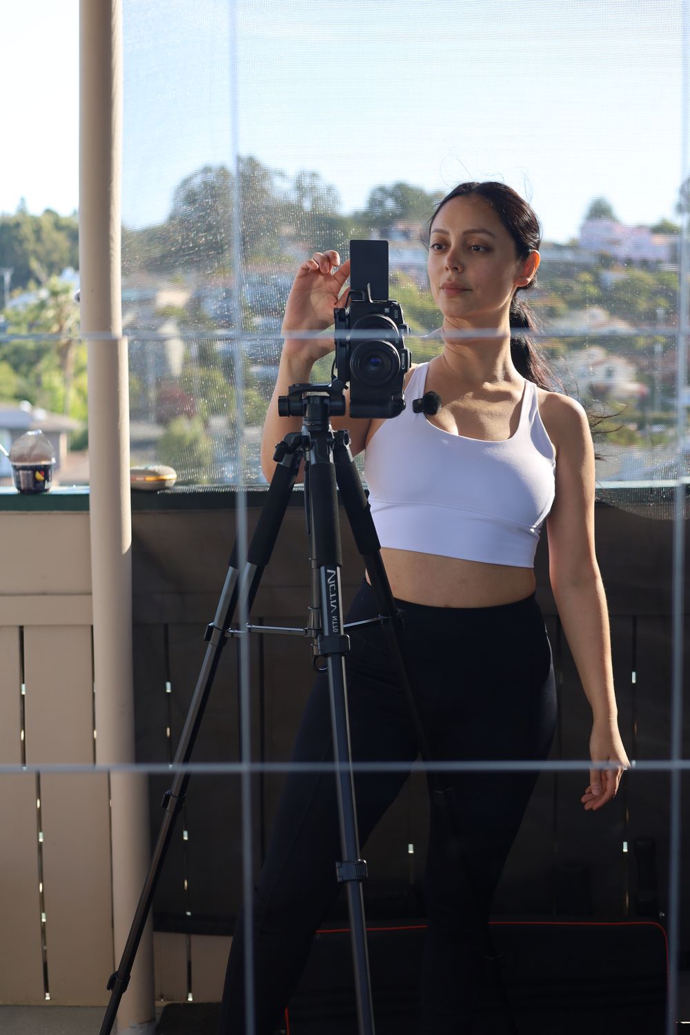 Angie setting up her camera on a tripod, Bay Area hills behind her