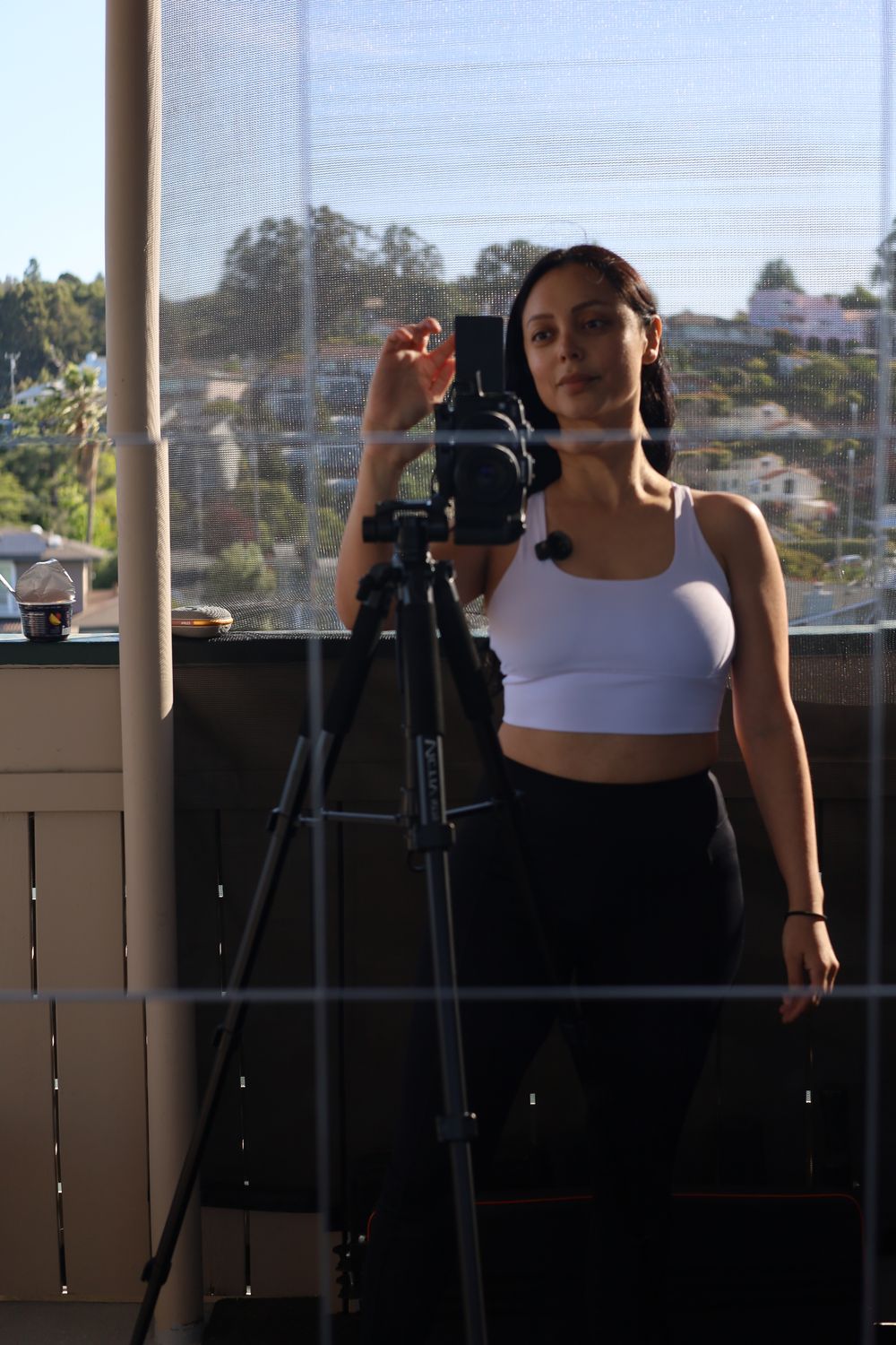 Angie standing beside her camera, looking toward the lens